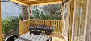 drewniany taras ze stołami i krzesłami w obiekcie Paradis Cap Ferret Location Mobil home Amira 42m2 ou Calina 31m2 w mieście Lège-Cap-Ferret +15 zdjęć
