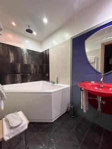 a bathroom with a tub and a red sink at Daytona Business Hotel in Collecchio