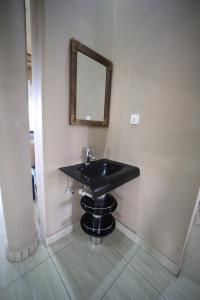 bagno con lavandino nero e specchio di OMX Hotel Remera a Kigali