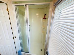 a glass shower in a bathroom next to a window at 2 Bedroom Caravan SHS3, Sandhills, Bembridge in Bembridge