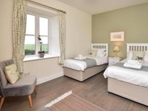 Un dormitorio con dos camas y una silla y una ventana. en 2 Bed in Bamburgh 92196, en Belford