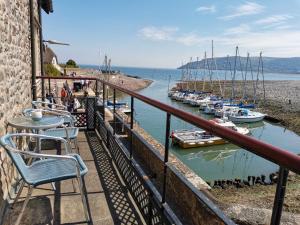 a balcony with tables and chairs and boats in the water at Harbour House Holiday Home in Porlock