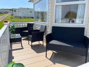 a screened porch with chairs and a table at 2 Bedroom Caravan SHS3, Sandhills, Bembridge in Bembridge +12 photos