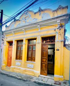 un edificio amarillo con puertas y ventanas de madera en A Casa dos Mestres en Salvador