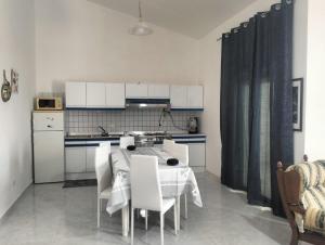 une cuisine avec une table et des chaises blanches et une cuisine avec des armoires blanches dans l'établissement Casa Vacanze da Francesca, à Realmonte