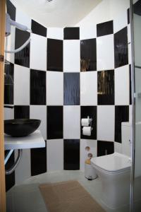 uma casa de banho com uma parede xadrez em preto e branco em Poseidon Apartments and Villas by the Sea em Sounio