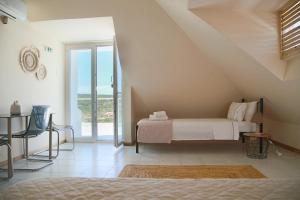 スーニオにあるPoseidon Apartments and Villas by the Seaの白いベッドルーム(ベッド1台、バルコニー付)