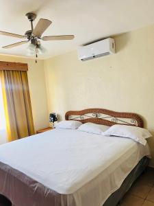 um quarto com uma cama branca e uma ventoinha de tecto em villa en palma real em La Ceiba