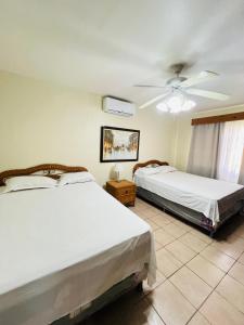 a bedroom with two beds and a ceiling fan at villa en palma real in La Ceiba