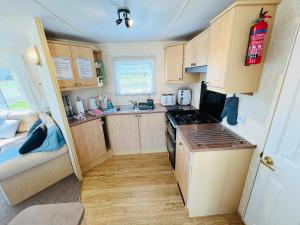 a small kitchen with wooden cabinets and a stove at 2 Bedroom Caravan SHS3, Sandhills, Bembridge in Bembridge