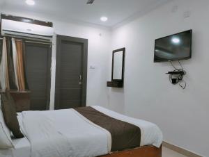 Hotel Maxx في لاكناو: غرفة نوم مع سرير وتلفزيون على الحائط