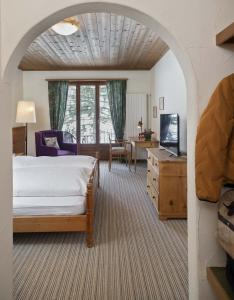 a bedroom with a bed and a desk and a table at Bad Serneus Water Resort in Klosters