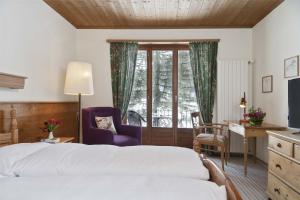 a bedroom with a bed and a desk and a window at Bad Serneus Water Resort in Klosters