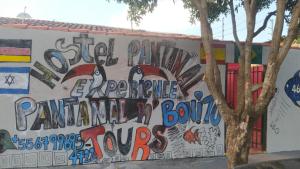 Hostel Pantanal Experience - Pantanal n' Bonito Tours في كامبو غراندي: جدار فيه كتابات على جانب مبنى