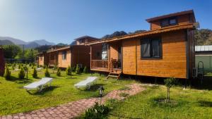 a log cabin with two benches in the yard at Ugur Pansiyon Bungalows in Cıralı