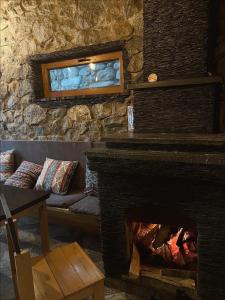 a living room with a fireplace and a stone wall at Guest House Nikala in Mestia