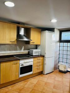 a kitchen with wooden cabinets and a white refrigerator at Travel Habitat - Ciudad de las Ciéncias in Valencia