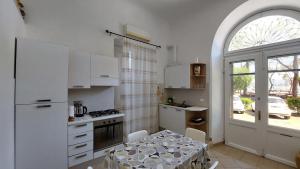cocina con armarios blancos, mesa y ventana en Cà da Ro en Fezzano