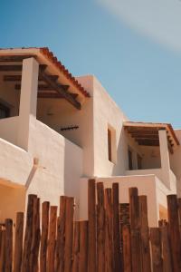 una casa blanca con una valla de madera delante de ella en Estel Formentera en Playa de Migjorn