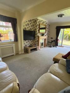 a living room with a couch and a tv on the wall at A Stunning 3 bed family Home - Woodcote House in Carshalton