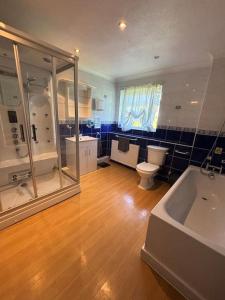 a bathroom with a tub and a toilet and a sink at A Stunning 3 bed family Home - Woodcote House in Carshalton