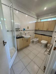 a bathroom with a toilet and a sink and a shower at A Stunning 3 bed family Home - Woodcote House in Carshalton