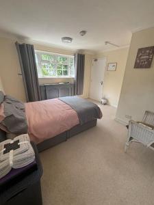 a bedroom with a bed and a window and a chair at A Stunning 3 bed family Home - Woodcote House in Carshalton