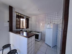 a small kitchen with a refrigerator and a stove at Casarão Pertinho da Praia in Bertioga