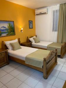 two beds in a room with yellow walls at Hotel Kuč in Budva