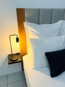 - un lit avec des oreillers blancs et une lampe sur une table dans l'établissement T1 - Le Tuit-Tuit 5* - 9' centre ville, à Saint-Denis