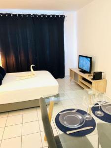 Cette chambre comprend un lit, une table et une télévision. dans l'établissement T1 - Le Tuit-Tuit 5* - 9' centre ville, à Saint-Denis
