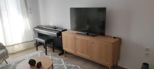 a living room with a flat screen tv and a piano at Eva's Suite in Serres