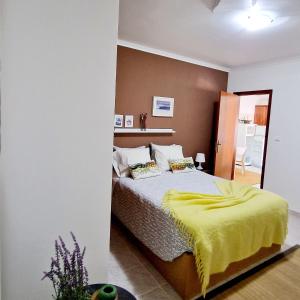 um quarto com uma cama com um cobertor amarelo em Porto Dinheiro Beach I na Lourinhã