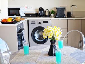 a table with a vase of yellow flowers and a washing machine at Kitieos Central Apartment with Sea View in Larnaca