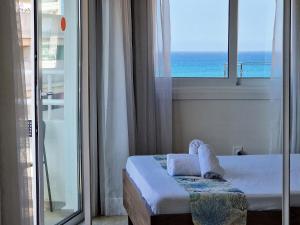 a bedroom with a bed and a window with the ocean at Kitieos Central Apartment with Sea View in Larnaca