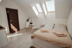 a white bedroom with a bed and a table at Apartamenty Kaszuba in Chmielno