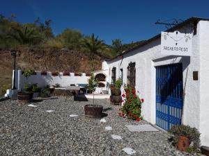 a white building with a blue door and some plants at Montana retreat in Alora