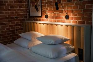 a bed with four pillows on it with a brick wall at Willa Bywaj Zdrój in Lądek-Zdrój