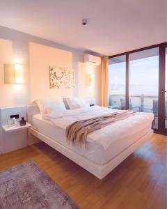 a bedroom with a large white bed with a large window at Batumi Orbi City in Batumi