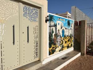 un murale sul lato di un edificio con cancello di Dar lamisse Djerba a Houmt Souk
