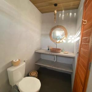 W łazience znajduje się biała toaleta i lustro. w obiekcie Chalé dos ventos Macapá w mieście Ponta do Anel