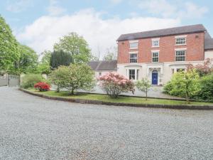 a large brick house with trees in the driveway at Rosehill Manor in Market Drayton