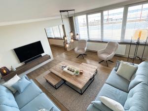 een woonkamer met een blauwe bank en 2 stoelen bij Eden-Beach in Oostende