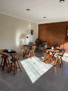 a room with tables and chairs and a brick wall at Pousada do valle in Monte Verde