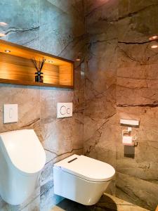 La salle de bains est pourvue de toilettes et d'un mur en pierre. dans l'établissement Villa de montagne avec piscine intérieure chauffée, à Bellefosse