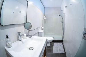 Un baño con lavabo, inodoro y espejo. en San Francisco, en Vigo