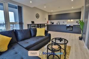 a living room with a blue couch and a kitchen at NEAR WEMBLEY STADIUM, FREE PARKING, 5 MIN FROM BRENT CROSS WEST STATION, SLEEPS 7 By HKM HOUSING Short Lets & Serviced Accommodation Cricklewood & BRENT CROSS in London