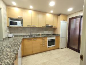 a kitchen with wooden cabinets and a white refrigerator at Paraíso Galera - Apartamento con piscina in Estepona