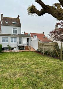 ein weißes Haus mit einem Hof und einem Zaun in der Unterkunft Gîte L'Estran à Equihen Plage équipée pour 6 personnes + 1 bébé in Équihen-Plage