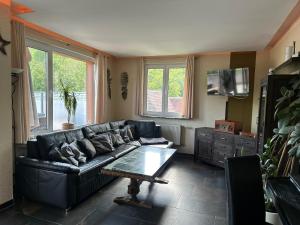 ein Wohnzimmer mit einem schwarzen Sofa und einem Tisch in der Unterkunft Ferienhaus Am Ettersberg in Ettersburg